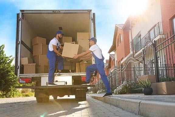 Movers packing boxes and loading furniture into a truck in Muscat